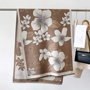 Detail of floral printed scarf with fringe edges hung with a beige trench coat