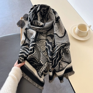 Thick faux cashmere scarf featuring leaf fringe and artistic patterns on table