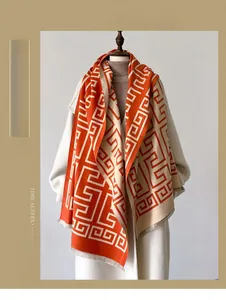 Detail view of winter scarf with orange geometric pattern and fringe trim on a mannequin