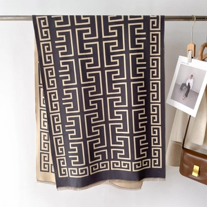 Detail of a black and beige Greek key patterned scarf with soft fringe edges for winter