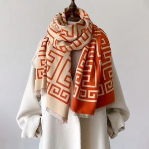 Orange and beige geometric knit scarf with tassels paired with a white winter coat