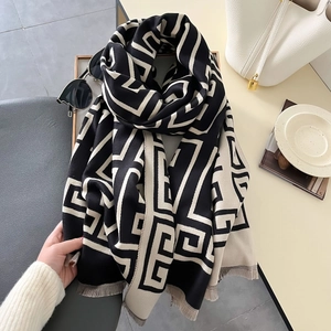 Detail of soft thick scarf featuring black and beige geometric greek key patterns and tassels