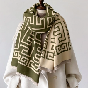 Detail of green and beige Greek key patterned scarf with fine tassel edges on a mannequin