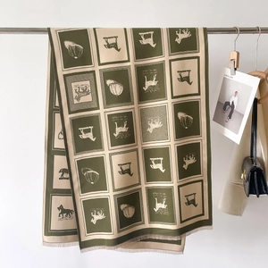 Detail of green and cream plaid scarf with horse patterns and short fringes