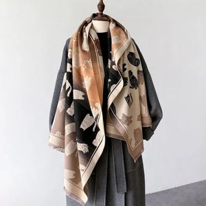Detail of winter knit scarf featuring cute cat silhouettes and fringe edges on a coat