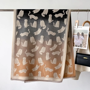 Detail of gradient knitted cat scarf with woven feline patterns and soft fringe trim