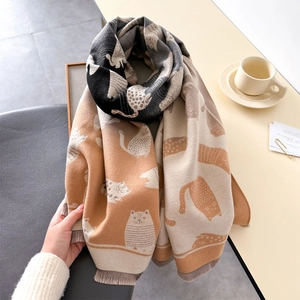 Close-up of thick knitted gradient scarf with cartoon cat pattern and soft tassels