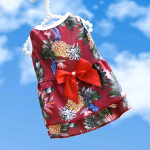 Détail de robe rouge pour animaux avec imprimé ananas, collier de perles et nœud en soie