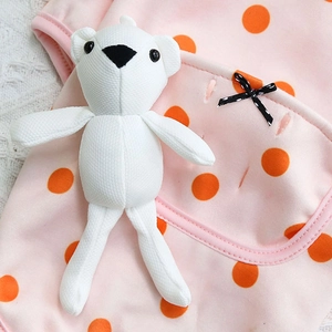 Detailed view of pink knitted pet clothes with orange polka dots and 3D plush bear