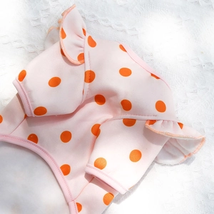 Close-up of pink pet shirt with orange polka dots and elegant ruffle trim details