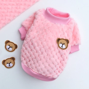 Detail of pink fleece pet sweater showing textured grid pattern and brown bear embroidery