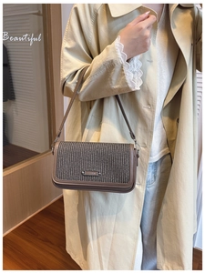 Detail of vintage woven texture on a brown crossbody bag worn with a beige trench coat