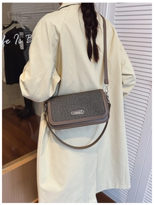 Detail of vintage woven crossbody bag with brown leather trim styled on a beige trench coat