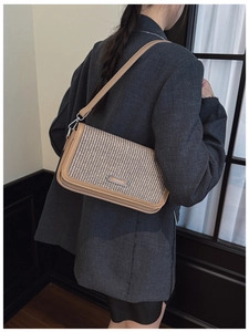Close-up of vintage brown leather woven crossbody bag with metal fashion logo plaque