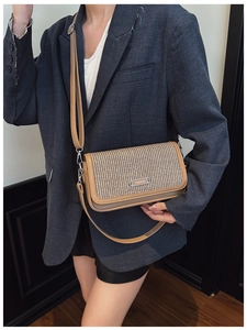 Detail view of woven crossbody bag with leather trim and gold fashion plate on a blazer