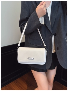Close-up of a white woven texture shoulder bag with silver FASHION metal plate detail