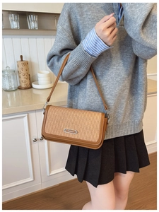 Detailed view of brown leather bag with woven texture panel and silver metal plate