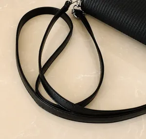 Close-up of comfortable black leather strap with silver buckle on woven handbag