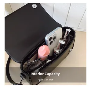 Internal capacity of the black leather crossbody bag showing phone and cosmetics