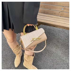 Detail of elegant two-tone handbag featuring gold U-shaped metal handle and woven texture