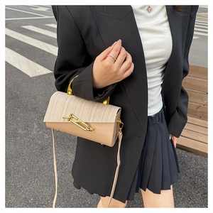 Detail view of beige PU leather bag with woven texture lid and gold geometric buckle