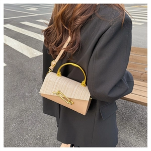 Detail view of the beige woven flap and light camel leather panel on a trendy box bag