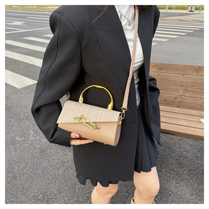 Detail showing the mixed-material shoulder bag with gold handle on a street style model