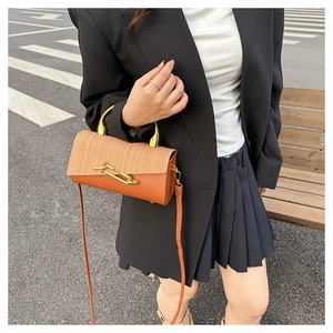 Detail view of structured orange PU and textured fabric handbag with gold pin buckle