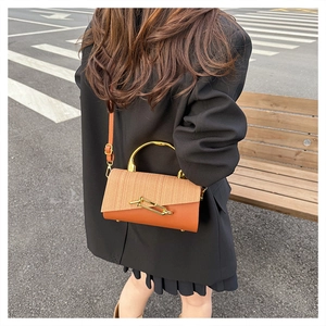 Detail of a chic PU leather and woven crossbody bag with gold metal handle and pin buckle