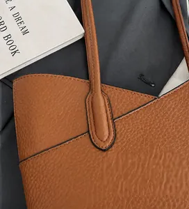 Detail of caramel leather tote bag with reinforced stitching and litchi texture