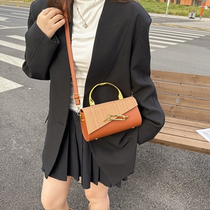 Orange leather and straw woven crossbody bag with gold metal handle on a model