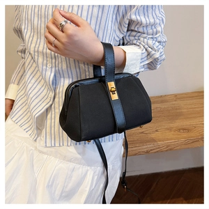 Detail of matte shell handbag featuring vintage gold metal clasp and leather handle straps