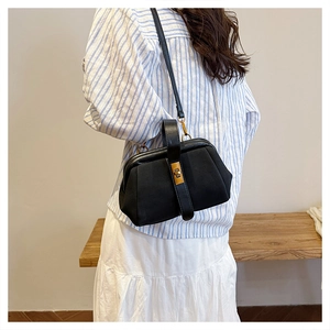 Side view of a vintage-style black matte shell bag with gold twist lock and shoulder strap