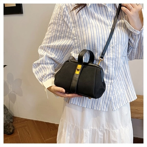Detail of a vintage black doctor bag with gold clasp and leather strap for crossbody wear