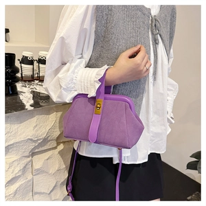 Detail of purple shell handbag showing matte suede texture and gold turn-lock closure