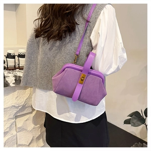 Detail of purple suede shell bag with gold metal clasp and adjustable shoulder strap
