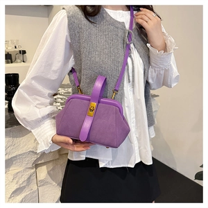 Detailed view of a purple shell-shaped bag with gold buckle and crossbody strap on a model