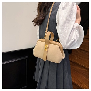 Detail of beige suede shell handbag featuring gold metal clasp and leather handle straps