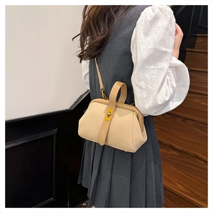 Detail of vintage beige shell bag with gold clasp and textured finish on model