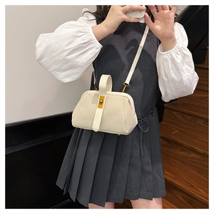Close-up of cream-colored matte shell bag featuring a golden metallic twist lock buckle