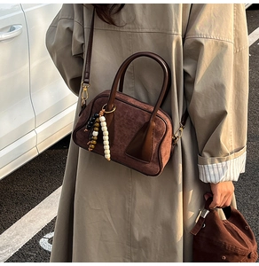 Detail of dark brown suede Boston bag with beaded pendant and adjustable strap