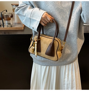 Close-up of khaki suede Boston bag with brown leather handles and vintage gold hardware