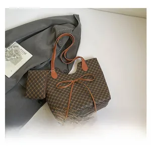 Détail de l'ensemble cabas imprimé et pochette avec un élégant nœud marron sur veste