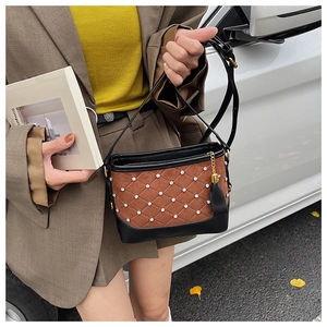 Detail of quilted brown suede bucket bag with rhinestone patterns and black leather trim