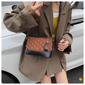 Close-up of quilted suede and black leather shoulder bag with gold tassel charm detail