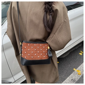 Detailed shot of brown quilted crossbody bag with rhinestone accents and leather tassels
