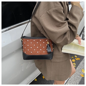Detail of diamond quilted crossbody bag with brown suede, black leather and fringe tassel