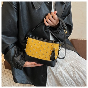 Detail of yellow quilted leather bag with crystal studs, tassels and slim black strap