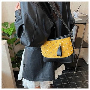 Detail of yellow quilted shoulder bag with rhinestones, black base and fringe tassel