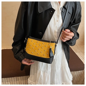 Detail of yellow and black quilted bag with rhinestones and fringe tassels on model